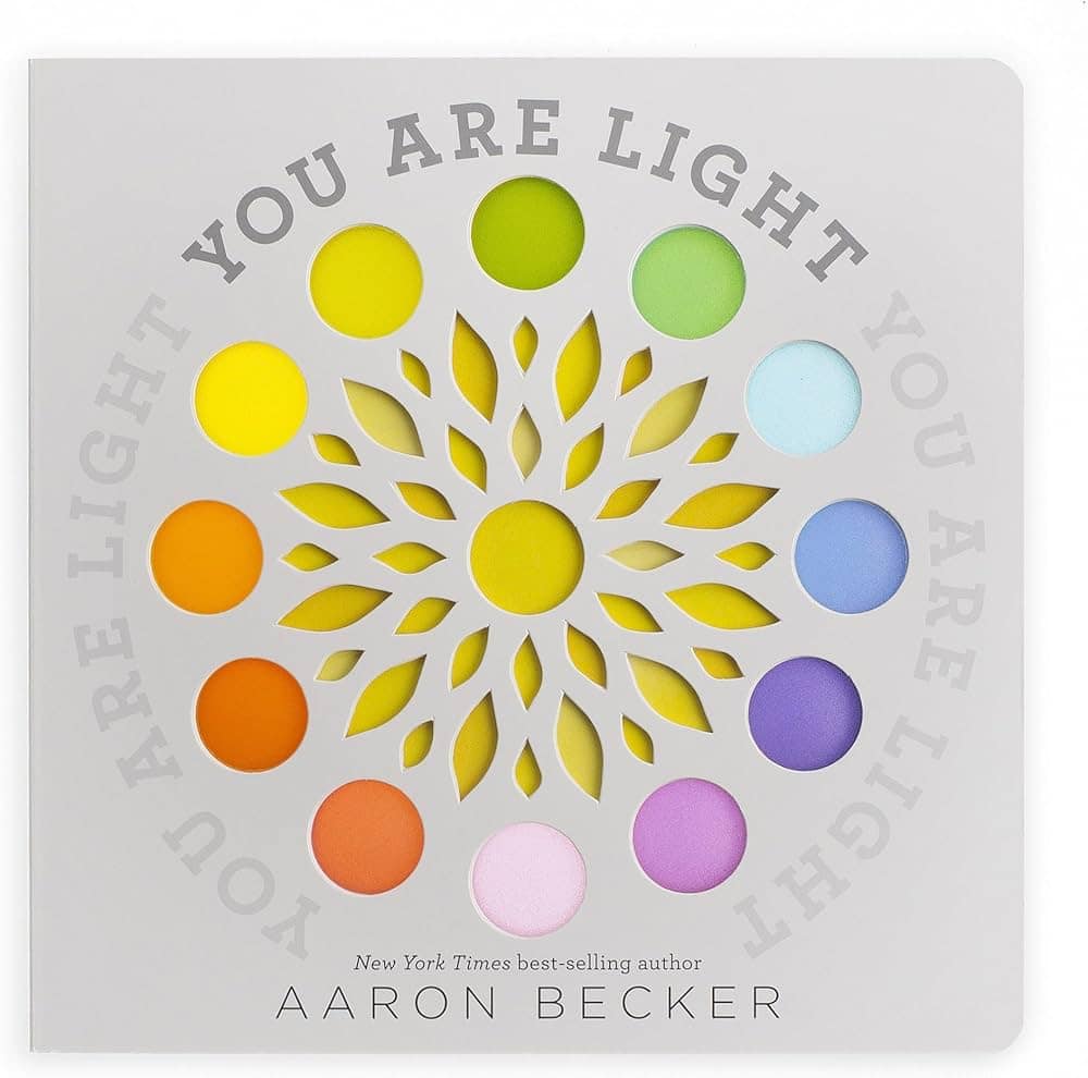 the cover of "you are light" by aaron becker features circular cutouts arranged in a sunburst pattern, displaying a spectrum of colors beneath the white cover.