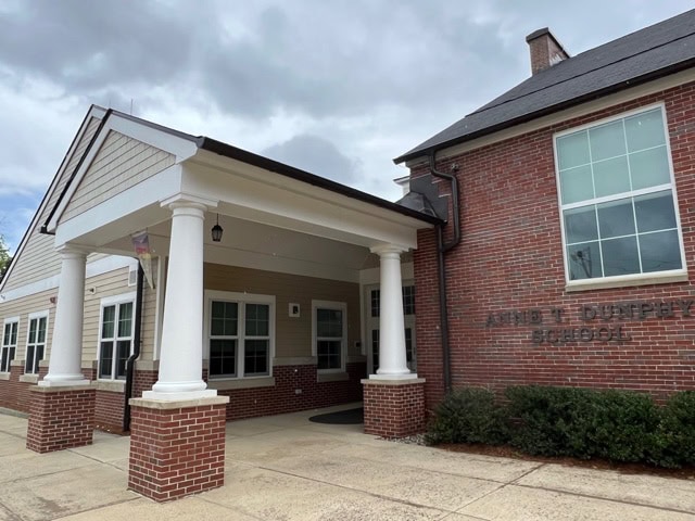 red brick school building with white columns at main entrance under a cloudy sky; “david e. dunphy school” is partially visible on the wall.