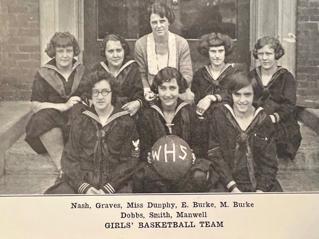 black and white photo of seven girls and one woman posing on steps, with a basketball labeled "whs." caption identifies them as the girls' basketball team with their names listed below.