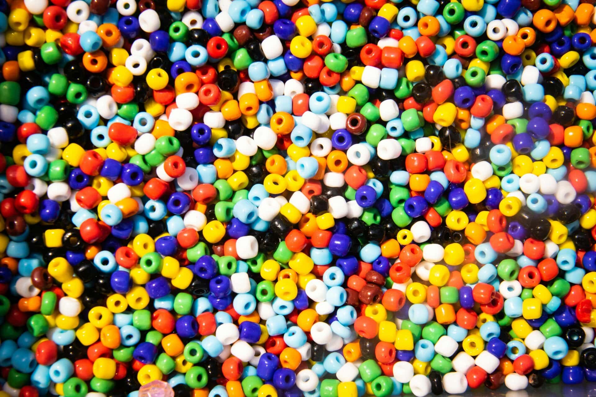 a close up view of a large pile of small, colorful plastic beads in various colors and randomly arranged.