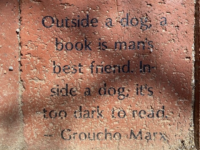 a red brick with an engraved quote: "outside a dog, a book is man's best friend. inside a dog, it's too dark to read. groucho marx.