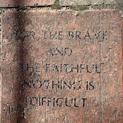 a weathered brick with the engraved words: “for the brave and the faithful nothing is difficult.”.