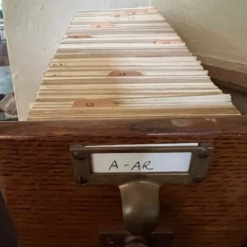 a wooden card catalog drawer labeled "a ar" is open, showing alphabetically organized index cards.