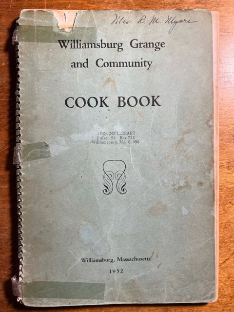 a worn, spiral bound 1952 cookbook titled "williamsburg grange and community cook book" with handwriting and visible tape on the cover.