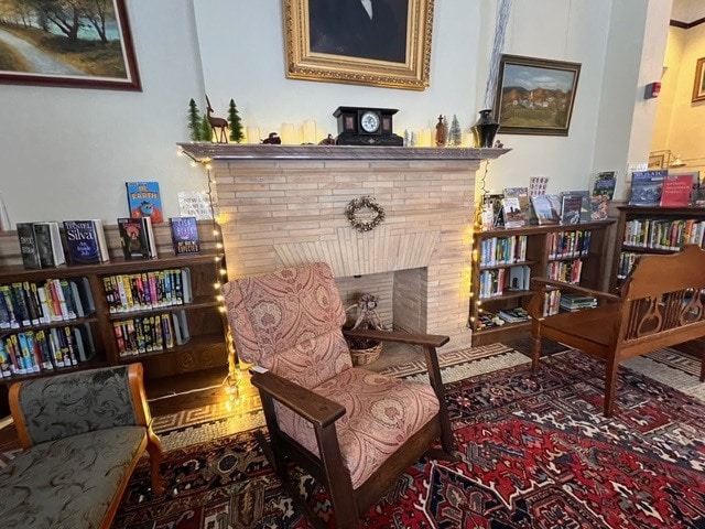 a cozy reading area in a library features an upholstered armchair in front of a decorated fireplace, flanked by bookshelves filled with books and small holiday lights.