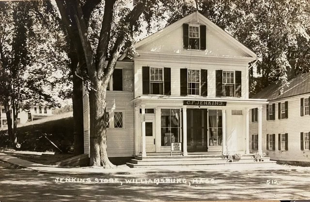 historic two story white building with sign "c.f. jenkins" above the entrance; labeled "jenkins store, williamsburg, mass." large tree in front, neighboring building on right.