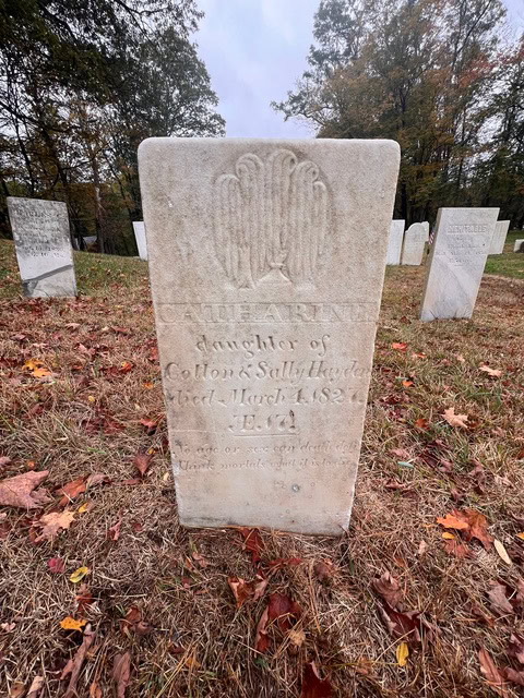 a weathered gravestone marks the grave of catharine, daughter of colton and sally hayden, who died march 1, 1832, in a cemetery with other headstones and autumn leaves on the ground.
