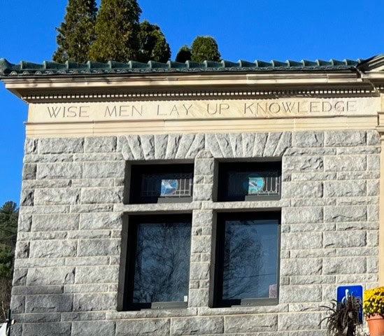 a stone building facade with two windows and the inscription 