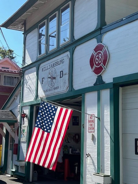an american flag hangs outside the williamsburg fire department engine house number 1, with a fire department emblem numbered 68 above the entrance.