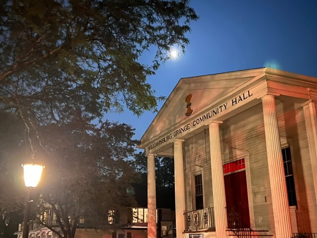williamsburg grange community hall at dusk, illuminated by a streetlamp, with trees and a bright moon visible in the sky.