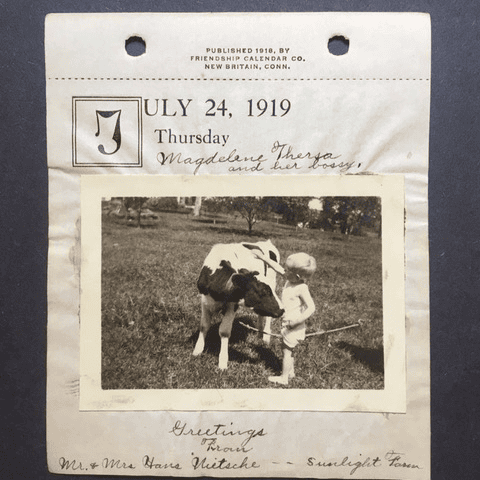 a black and white photo of a small child standing next to a calf on a july 24, 1919 calendar page, with handwritten notes and greetings below the photo.