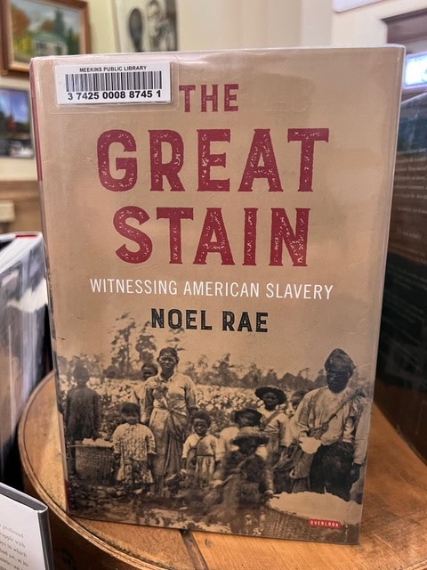 the cover of "the great stain: witnessing american slavery" by noel rae, featuring an archival photo of enslaved people, displayed in a library.