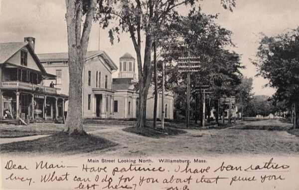 black and white postcard of main street in williamsburg, massachusetts, showing historic buildings and trees, with handwritten text at the bottom.