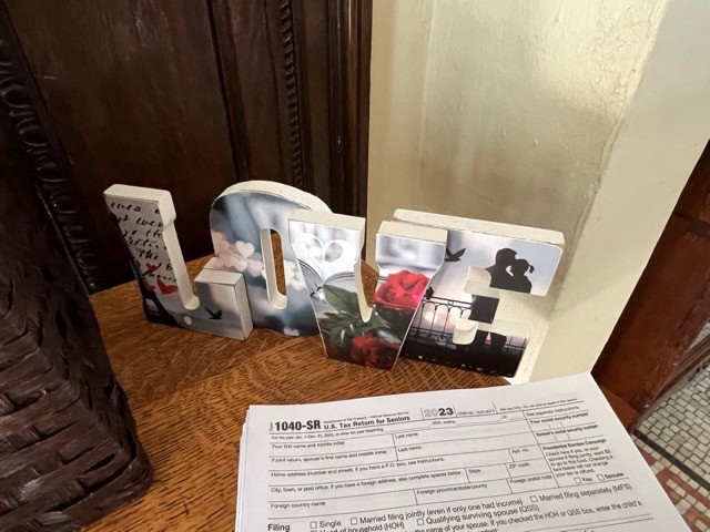 a decorative "love" sign sits on a wooden cabinet next to a 1040 sr tax form on a table.