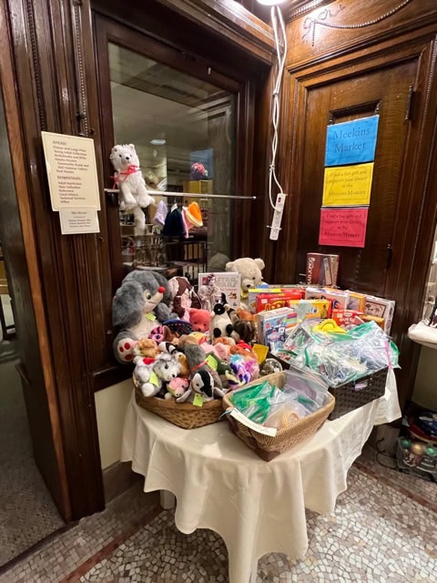 a round table and basket display a variety of stuffed animals, toys, and small items for sale in a wood paneled indoor market setting.