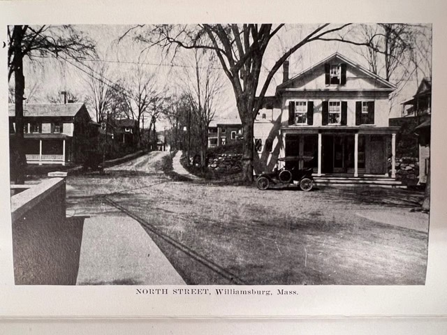black and white photo of north street in williamsburg, massachusetts, showing early 20th century buildings, leafless trees, and a vintage car parked in front of a house.
