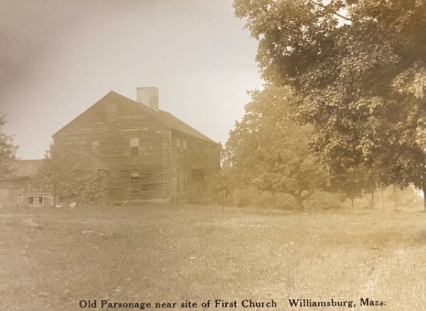 old wooden house with visible wear stands near trees in a grassy area. text below reads: 