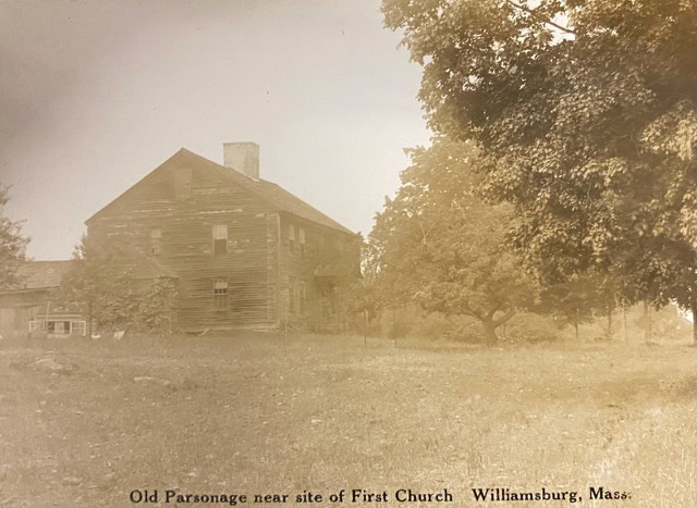old wooden house with visible wear stands near trees in a grassy area. text below reads: "old parsonage near site of first church, williamsburg, mass.
