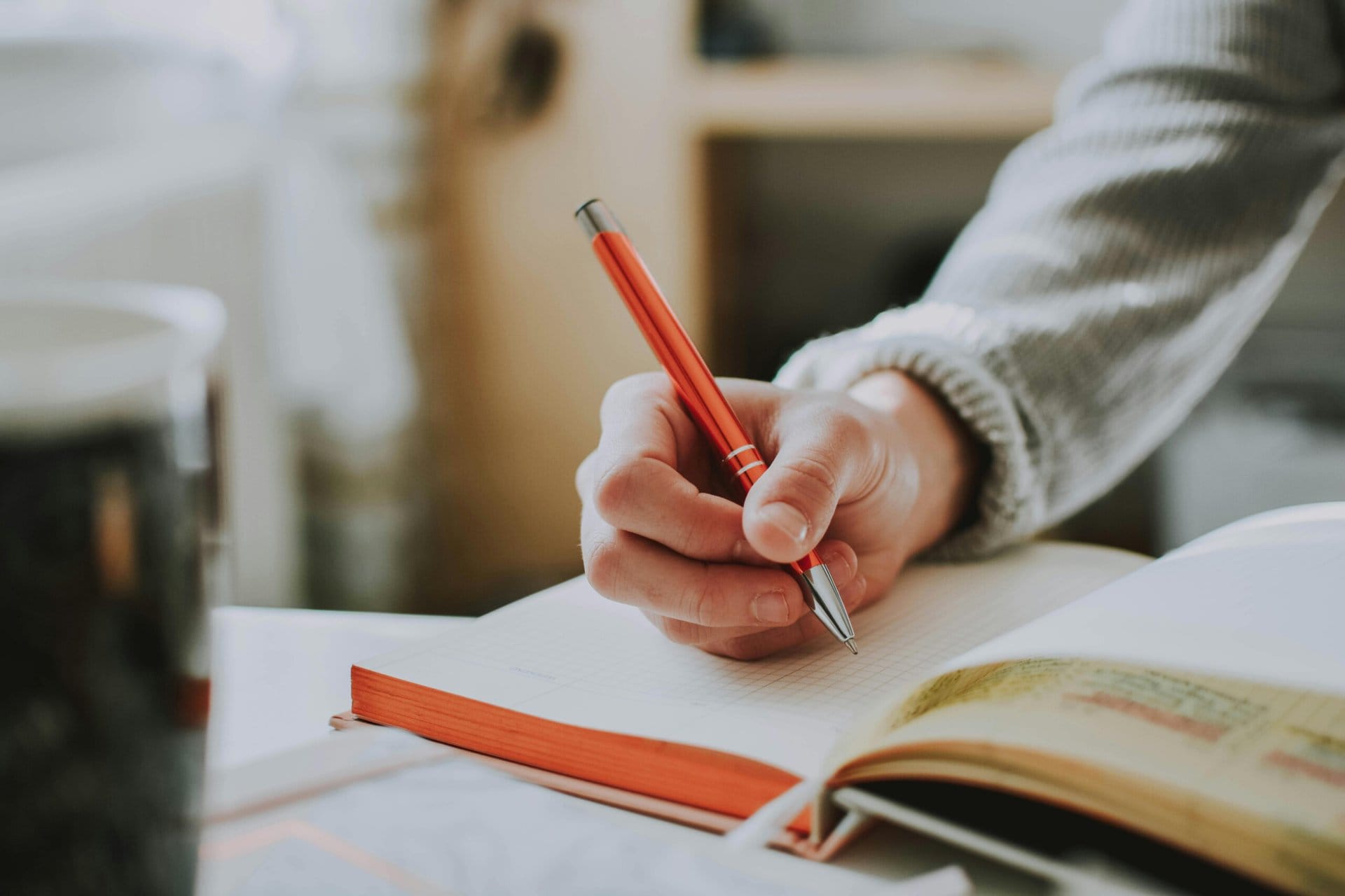 a hand holding a pen in a notebook. a hand holding a pen in a notebook.