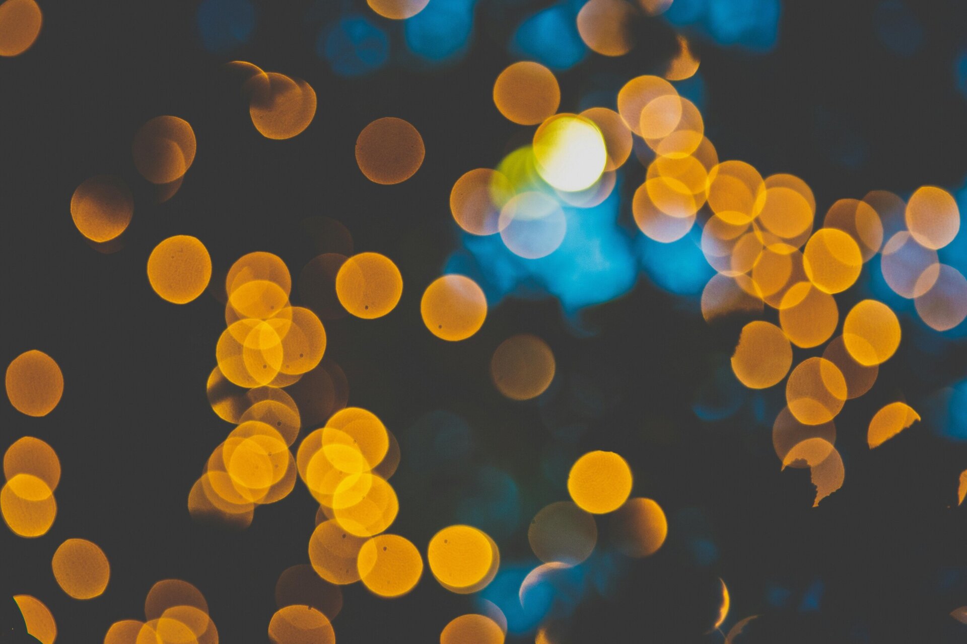 blurred yellow and orange lights create a bokeh effect against a dark blue and black background.