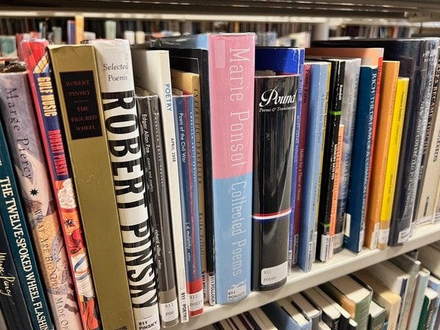 a shelf of library books focused on poetry, showing spines with titles and authors including robert pinsky, marie ponsot, and ezra pound.