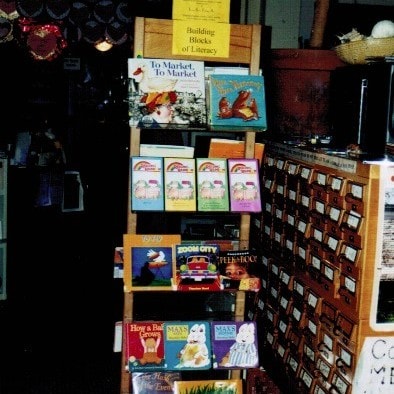 a wooden book display labeled "building blocks of literacy" holds various children's books in a library or bookstore setting.
