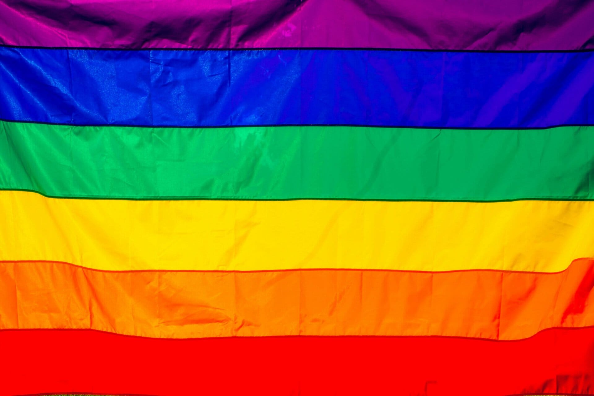 a rainbow flag featuring six horizontal stripes in purple, blue, green, yellow, orange, and red.