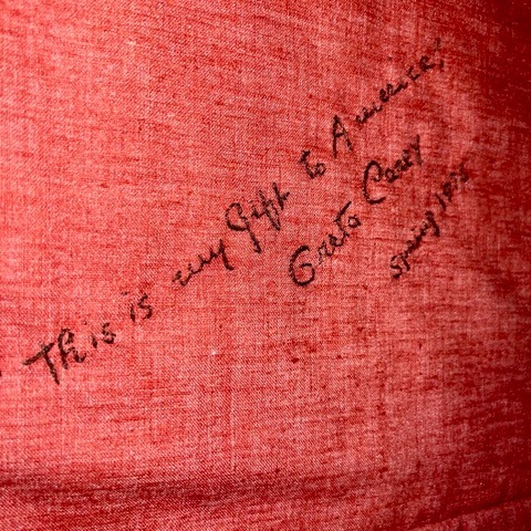 handwritten text on red fabric reads: “this is my gift to america, greta garbo, spring 1939.”.