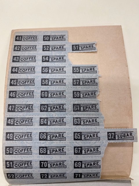 a sheet of vintage ration coupons labeled for coffee, spare, and sugar, numbered from 41 to 71, partially attached to a brown paper backing.