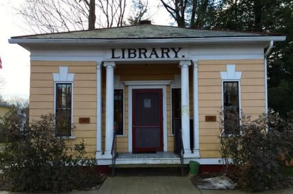 the haydenville library exterior - A small, yellow, single-story building with white columns and a sign reading 