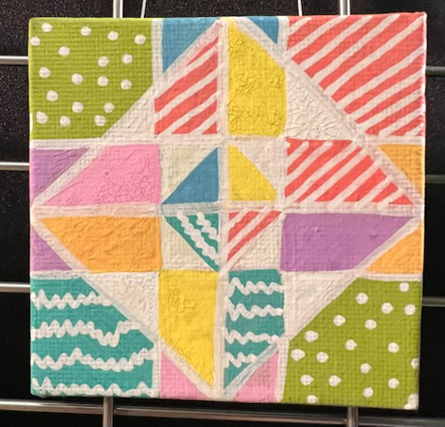 a square ceramic tile features a geometric pattern with colorful triangles and rectangles, decorated with stripes, dots, and squiggles in white, pink, green, yellow, orange, and purple.