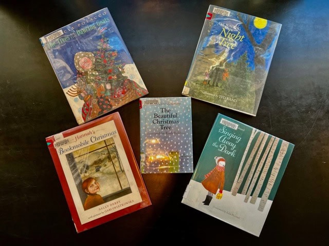 five christmas themed books are arranged on a dark surface, with covers visible and titles related to christmas trees and holiday stories.
