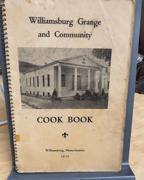 spiral bound cover of the "williamsburg grange and community cook book," published in williamsburg, massachusetts, in 1952, with a photo of a white building on the front.