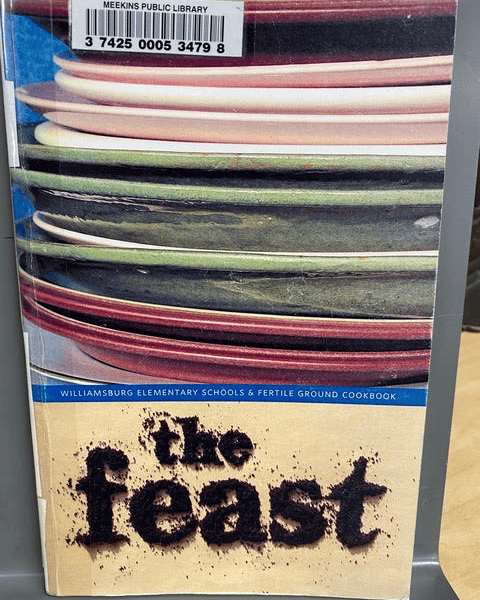 cover of a cookbook titled "the feast" with stacked plates in the background; published by williamsburg elementary schools & fertile ground. library barcode sticker at the top.