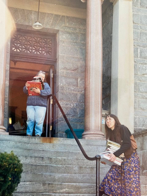 a woman carrying books on stairs.